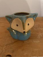 Front side view of the small blue fox clay planter showing facial features and glaze