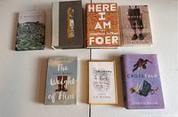 Photo shows seven books arranged flat on a white surface with titles visible.