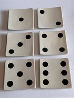 Top view of all six ceramic square plates showing domino face designs from one to six black pips on a cream background.