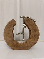 Front view of sculpture showing mango wood crescent base and two linked metal human figures representing teamwork.