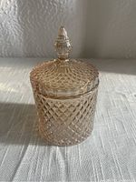 Front view of a small textured glass jar with a fitted lid and pointed knob handle, showing the diamond-pattern texture on glass.