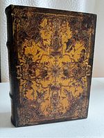 Full view of the decorative storage book showing the front cover with vintage illustrations and worn edges