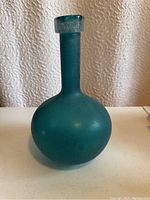 Opaque teal blue-green seaglass vase with rounded base and narrow neck with flat rim.