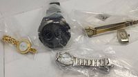 Five wristwatches sealed in plastic bags, different styles and sizes shown grouped together.