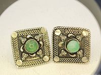 Front view of square silver earrings with green jade stones in the center and detailed border.