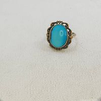 Front view of turquoise ring showing bright blue oval stone and detailed metalwork around the setting.