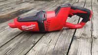 Side profile of Milwaukee red and black handheld vacuum cleaner on wooden surface