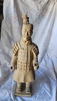 Front view of handmade wooden standing Asian warrior carving with detailed armor and facial features, showing the full figure on a rectangular base.