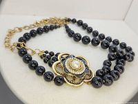 Front view of vintage necklace showing black beads and large flower pendant with central Mabe pearl.
