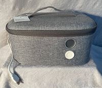 Gray fabric rectangular sanitizer bag with USB cable attached, power button and handle on top.