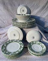 Image showing the full set of dishes including stacked plates, bowls, and saucers, displaying the moss ivy green leaf pattern around edges.