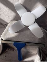 Four white adjustable panels of the LED garage light and blue handle of the squeegee visible