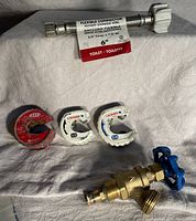 Photo of 3 pipe cutters, a brass garden hose tap with blue valve handle, and a new flexible stainless steel toilet connector with labels.