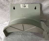 Grey semi-circular hose hanger with two screw hole mounts shown from front on fabric background
