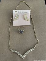 Full set laid out on surface, includes necklace, earrings mounted on card, and ring placed below.