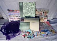 Overview photo of scrapbooking bundle including two albums, purple die cut templates, and various sticker and paper packages spread on table