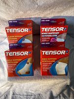 Front view of Tensor support bandages packaging showing four items: 1 elbow support, 2 knee supports, and 1 ankle support, all size large and white.