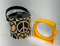 Overview photo showing both the peace sign ice bucket and yellow plastic mirror on stand together, highlighting their size and color contrast.