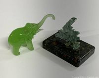 Photo showing the green jadeite elephant figurine with trunk raised and the Newfoundland stone souvenir with polished dark stone base side by side.