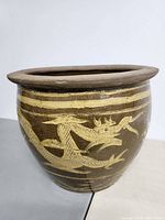 Side view showing the full dragon design in raised lighter clay against dark brown glaze.