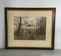 Framed and matted original watercolour painting showing a landscape scene with vegetation and barn under cloudy sky.