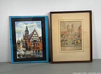 Two framed artworks side by side; left is a print with blue mat, right is a watercolour with beige mat and brown frame.