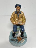 Front view of The Seafarer figurine showing seated man with pigeons.