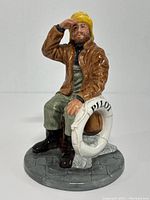 Front view of the Royal Doulton figurine showing the pilot seated with life preserver, detailed facial features, and clothing.