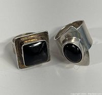 Two sterling silver rings with black onyx stones displayed side by side, showing front and top details.