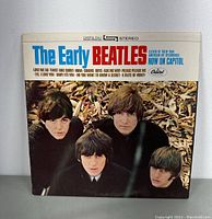 Front album cover photo featuring The Beatles in black clothing with blue and red text on top reading 'The Early Beatles'.