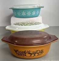 Front view showing stacked Pyrex casserole dishes in turquoise, yellow and orange with distinctive patterns and lids