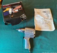 Air impact wrench with original manual and box on green cloth background