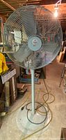Full frontal view of the large 24-inch Chelsea industrial air circulator fan showing the metal protective grille, blades, and pedestal base in a workshop setting.