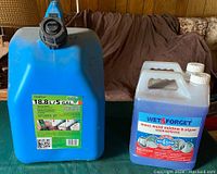 Blue 5 gallon/18.8L Scepter kerosene plastic container with label visible and one Wet & Forget moss, mold, mildew & algae stain remover bottle.