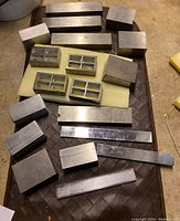 Top-down view of assorted rectangular and square metal setup blocks arranged on a surface showing size variations and surface finish.