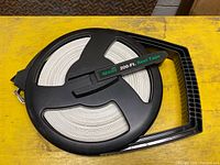 Black plastic Sears reel tape with white tape and green Sears 200-Ft Reel Tape label, showing spool and handle.
