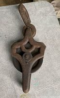 Front view of vintage cast iron barn hay pulley showing hook and wheel assembly