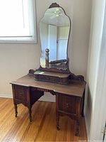 Front view of antique wooden vanity table with attached mirror and drawers, showing wood finish and wear.