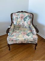Front view of vintage floral armchair showing floral fabric upholstery and carved wooden frame
