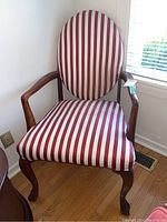 Full view of the wooden frame chair with red and white striped upholstery showing the curved armrests and oval backrest.