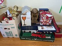 Overview of lot with Christmas ornament boxes, a gold-tone angel statue, luggage scale, and the packed broken wooden train parts