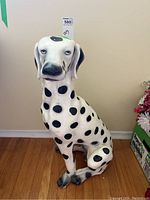 Full view of the plaster Dalmatian statue sitting on wood floor against a beige wall.