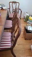 Side view of multiple dining chairs with red and beige striped upholstery, showing chair backs and seats.