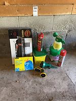 Photo showing boxed Hibachi BBQ grill with grilling racks and wooden handles, assorted spray cans, fertilizers, sprayers, nozzles, and a box of biodegradable garbage bags.