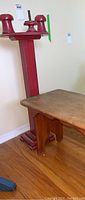 Photo showing wooden stool next to a red vertical stand with four pronged top.