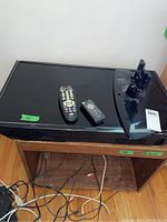 Top view of Insignia TV with two remote controls on top and wooden TV stand underneath.