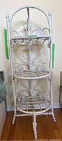 Full view of the white painted wicker three-tier plant shelf showing front and legs.