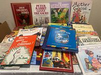 Photo showing a large collection of 35 children's books mostly hardcover with vibrant covers including Dr. Seuss and classic titles, arranged in overlapping layers on a flat surface.