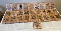 Front view photo showing all 28 wooden flower rubber stamps arranged in three rows on a table.