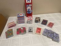 Photo of all sealed decks of playing cards arranged on a table including Bicycle, Aviator, Jack Daniels, Spider-Man, Coca-Cola, and generic decks.